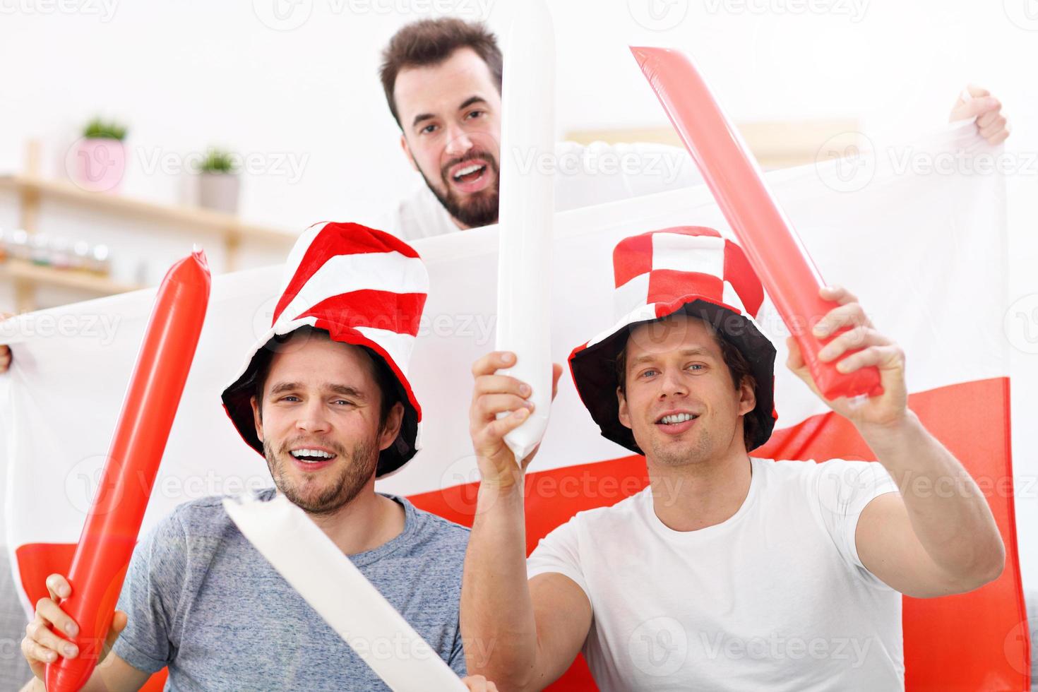Happy male friends cheering and watching sports on tv photo