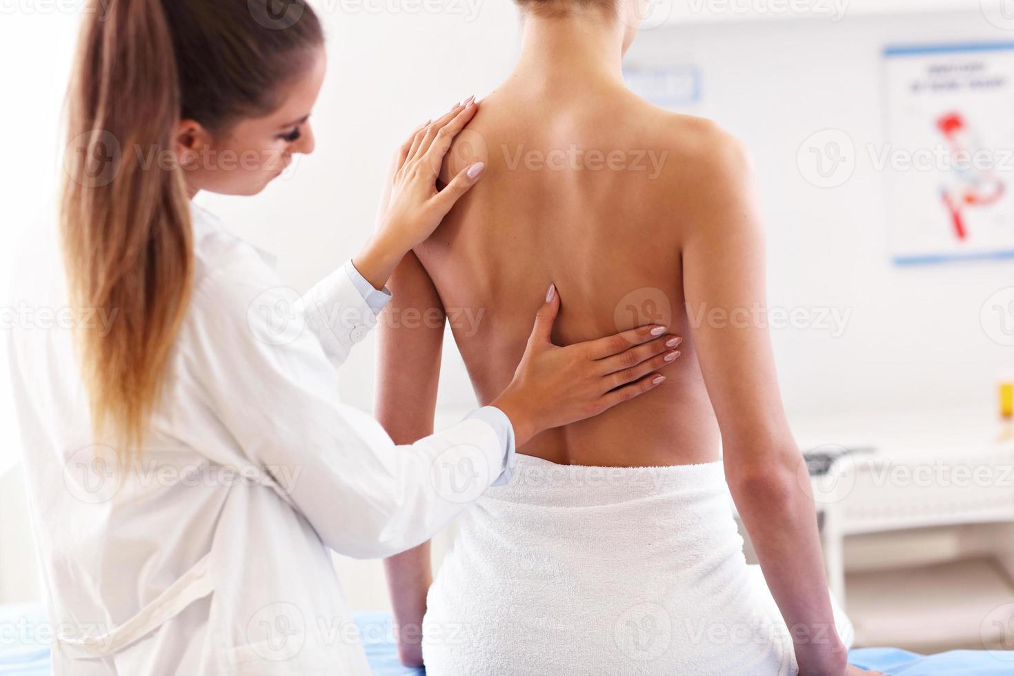 fisioterapeuta femenina ayudando a un paciente con problemas de espalda en la clínica foto