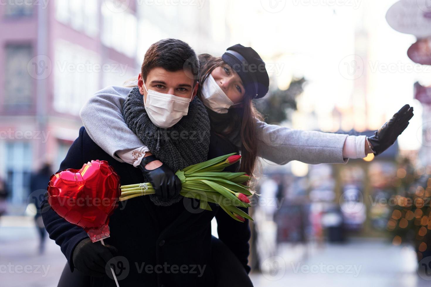 pareja feliz celebrando el día de san valentín con máscaras durante la pandemia de covid-19 foto