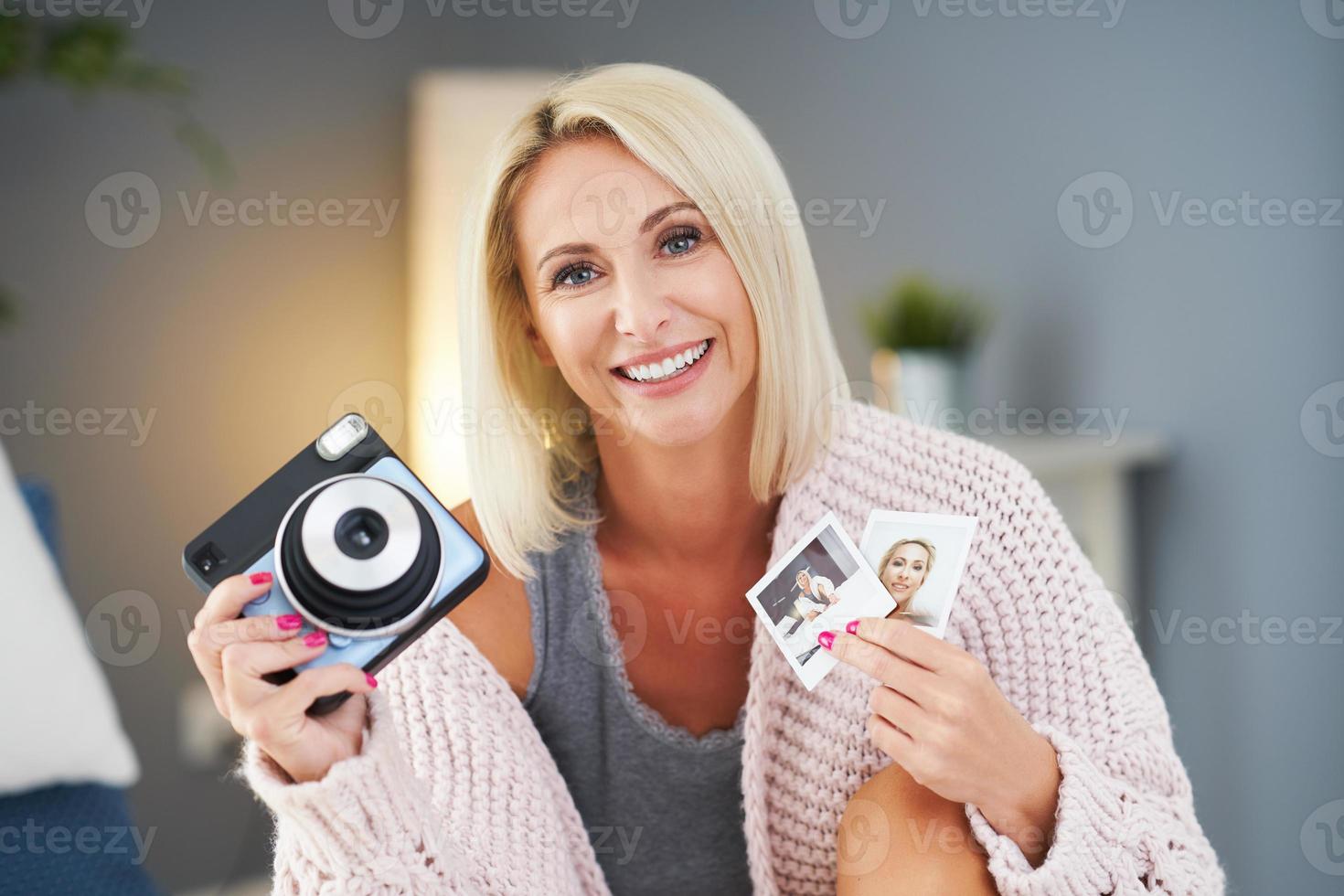 Adult beautiful woman taking instant photo at home