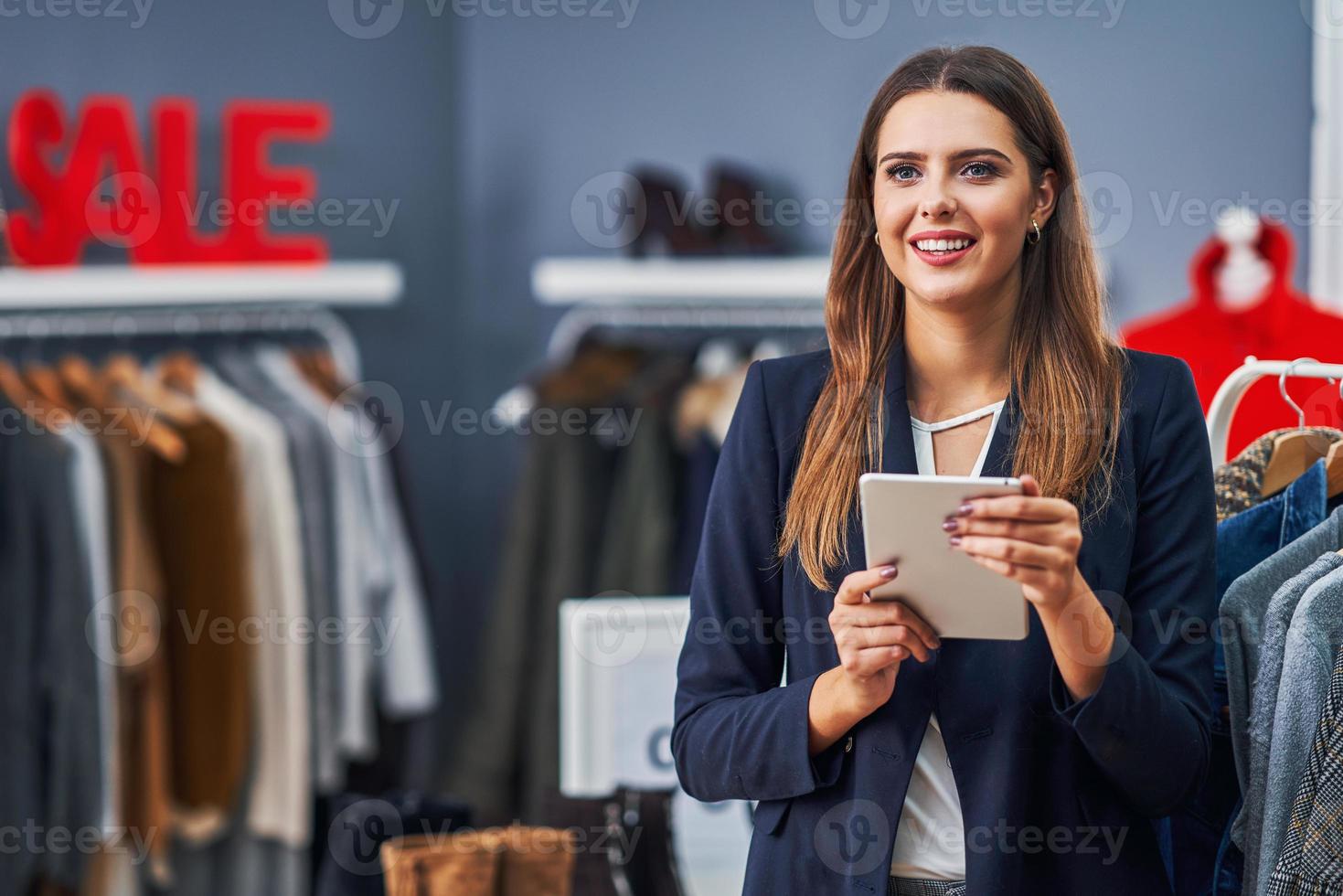 asistente de tienda feliz en su boutique con colección de otoño de invierno foto