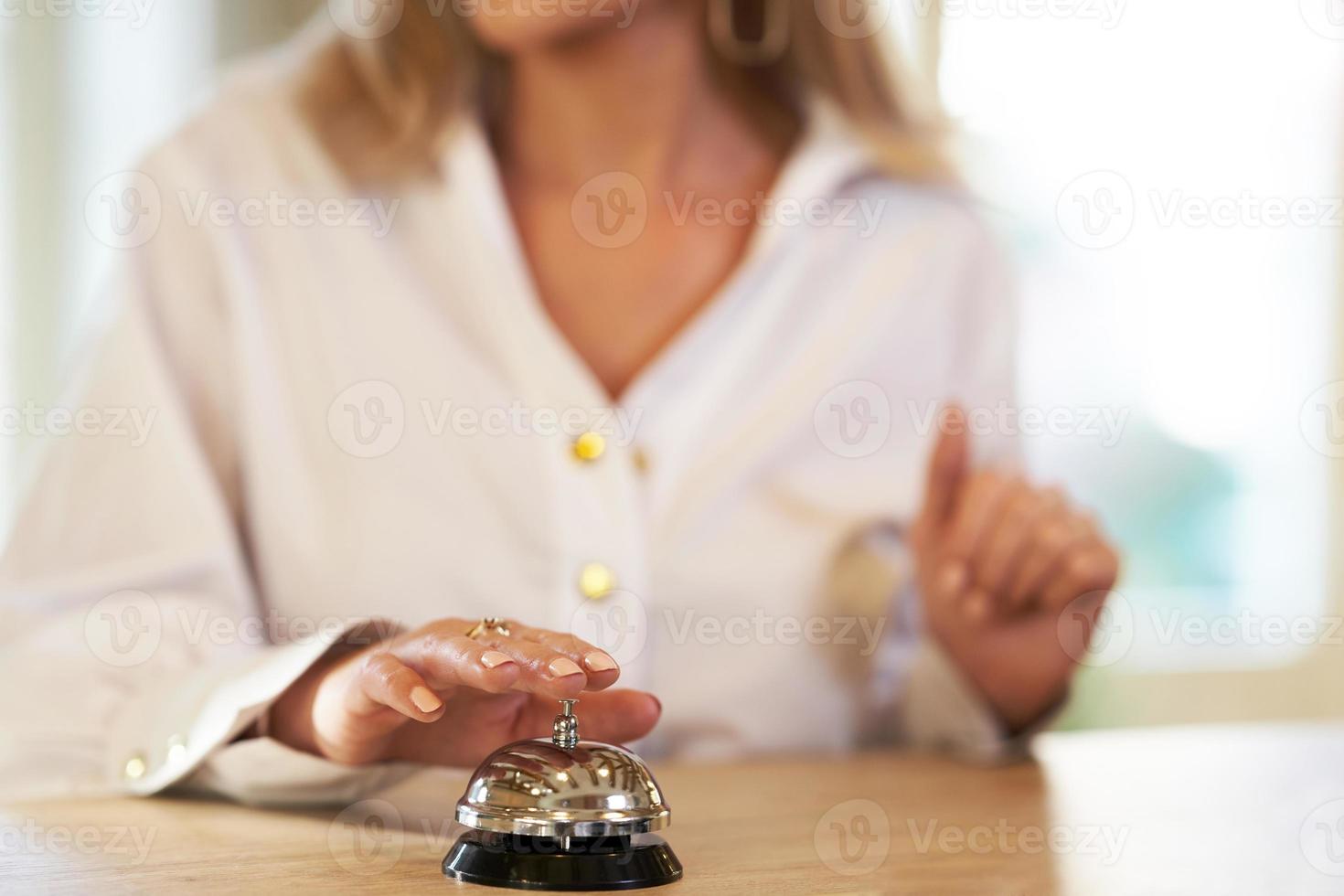 Businesswoman using bell at hotel front desk photo