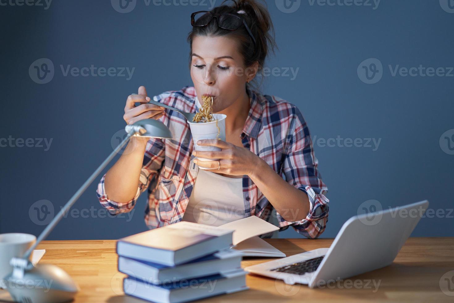 Hungry student eating noodle while learning at home photo