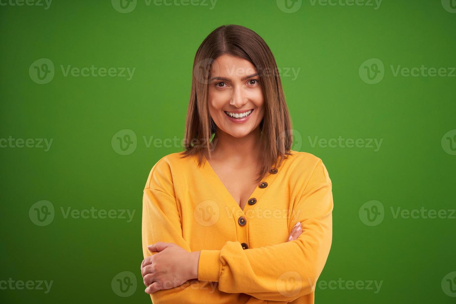 Close up of woman in yellow sweater looking at camera over green background photo