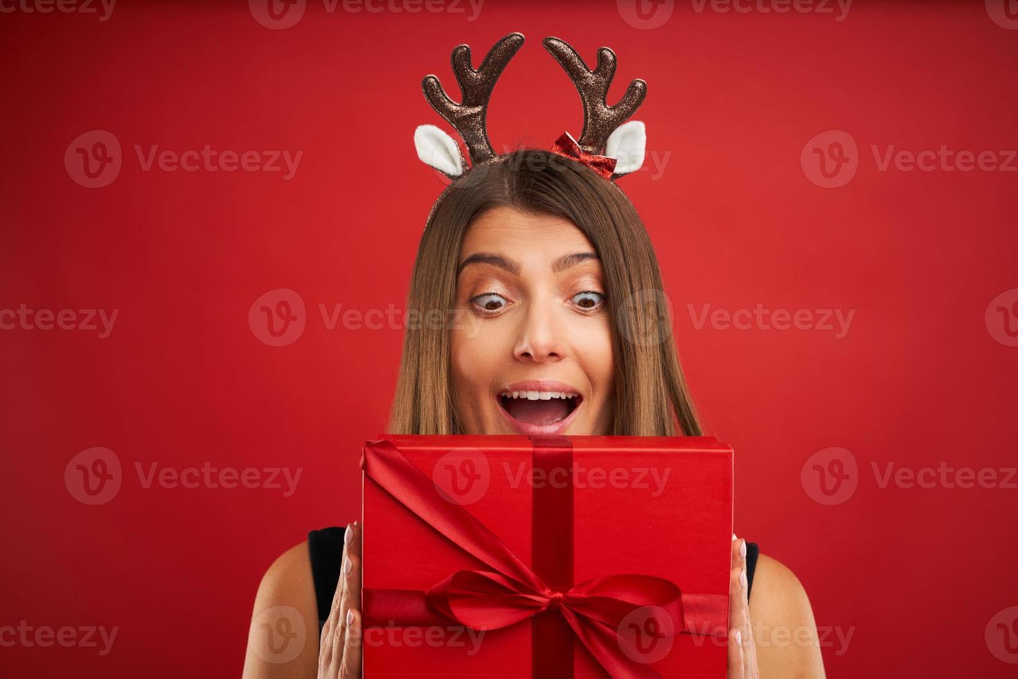 Adult happy woman with Christmas gift over red background photo