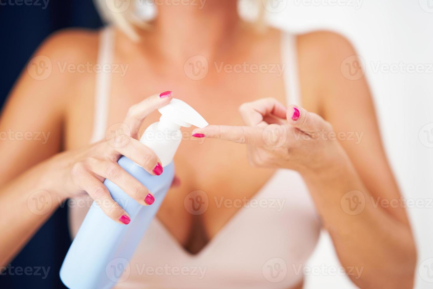 Adult woman applying body moisturizer photo