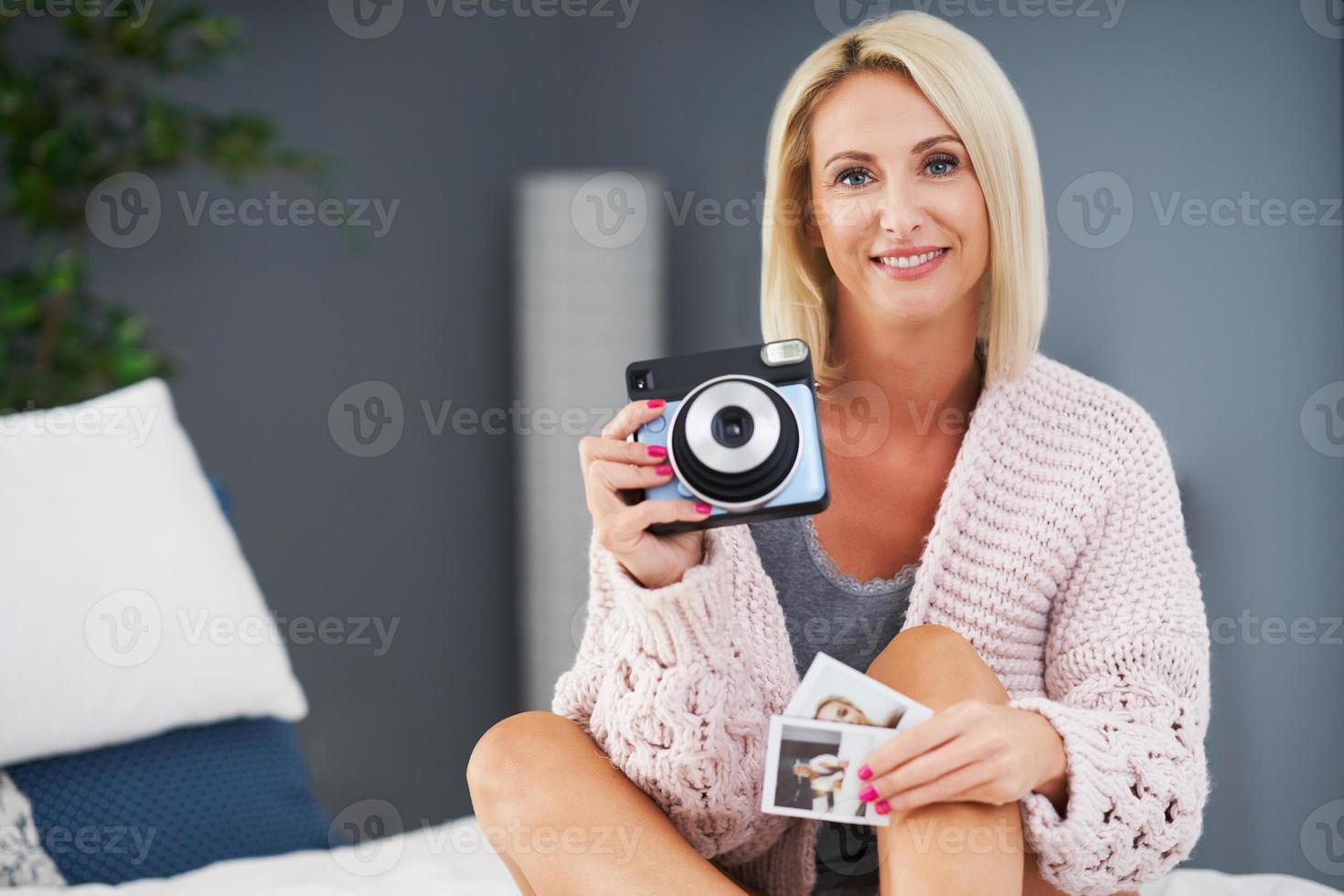 Adult beautiful woman taking instant photo at home