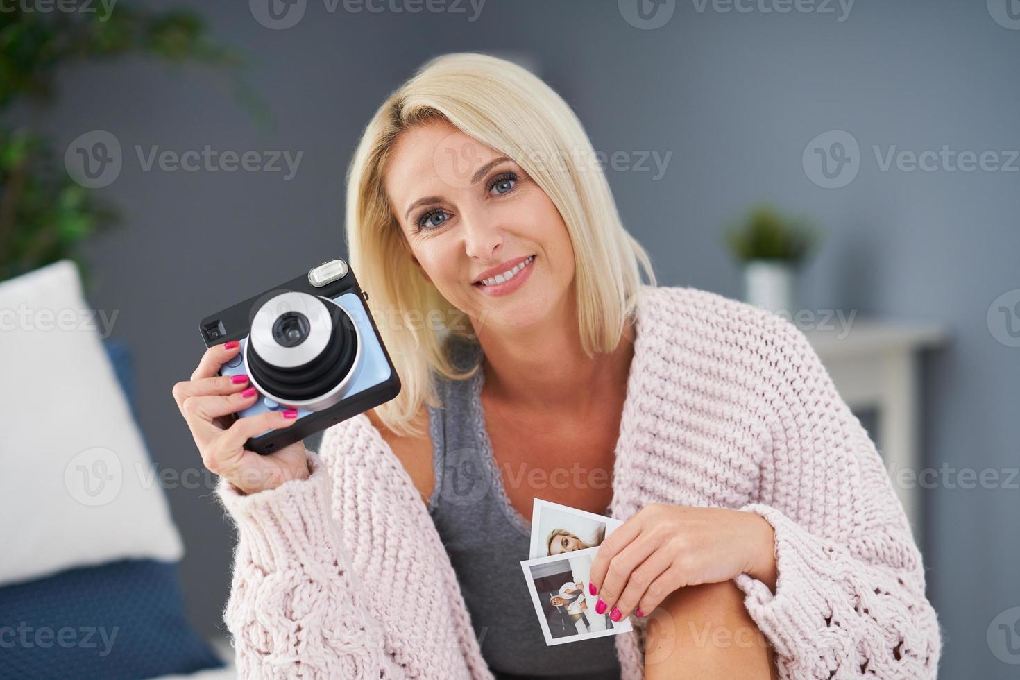 Adult beautiful woman taking instant photo at home