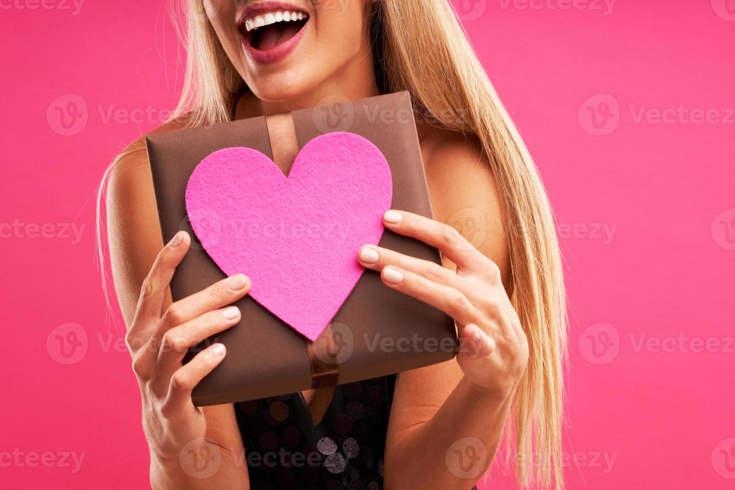 Beautiful adult woman posing over pink background with present photo