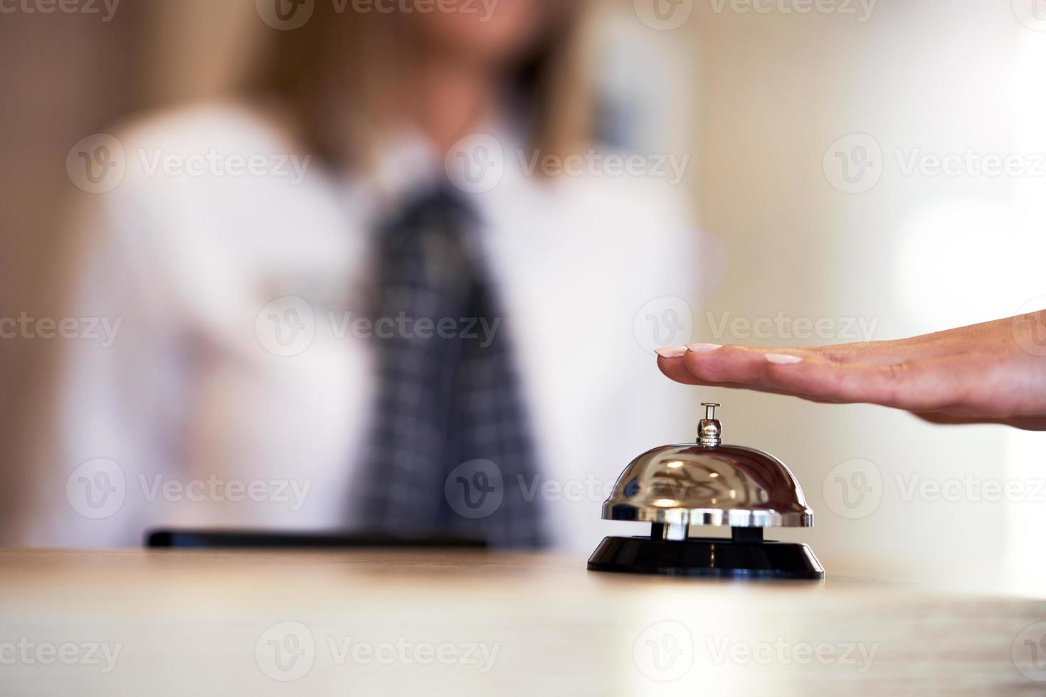 Hotel bell at front desk and receptionist in background photo