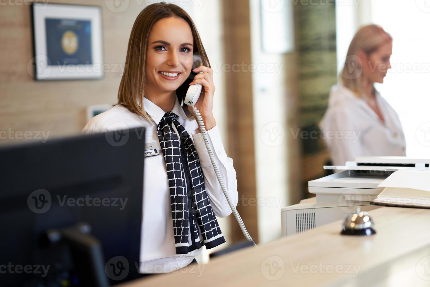 Receptionist answering phone at hotel front desk photo