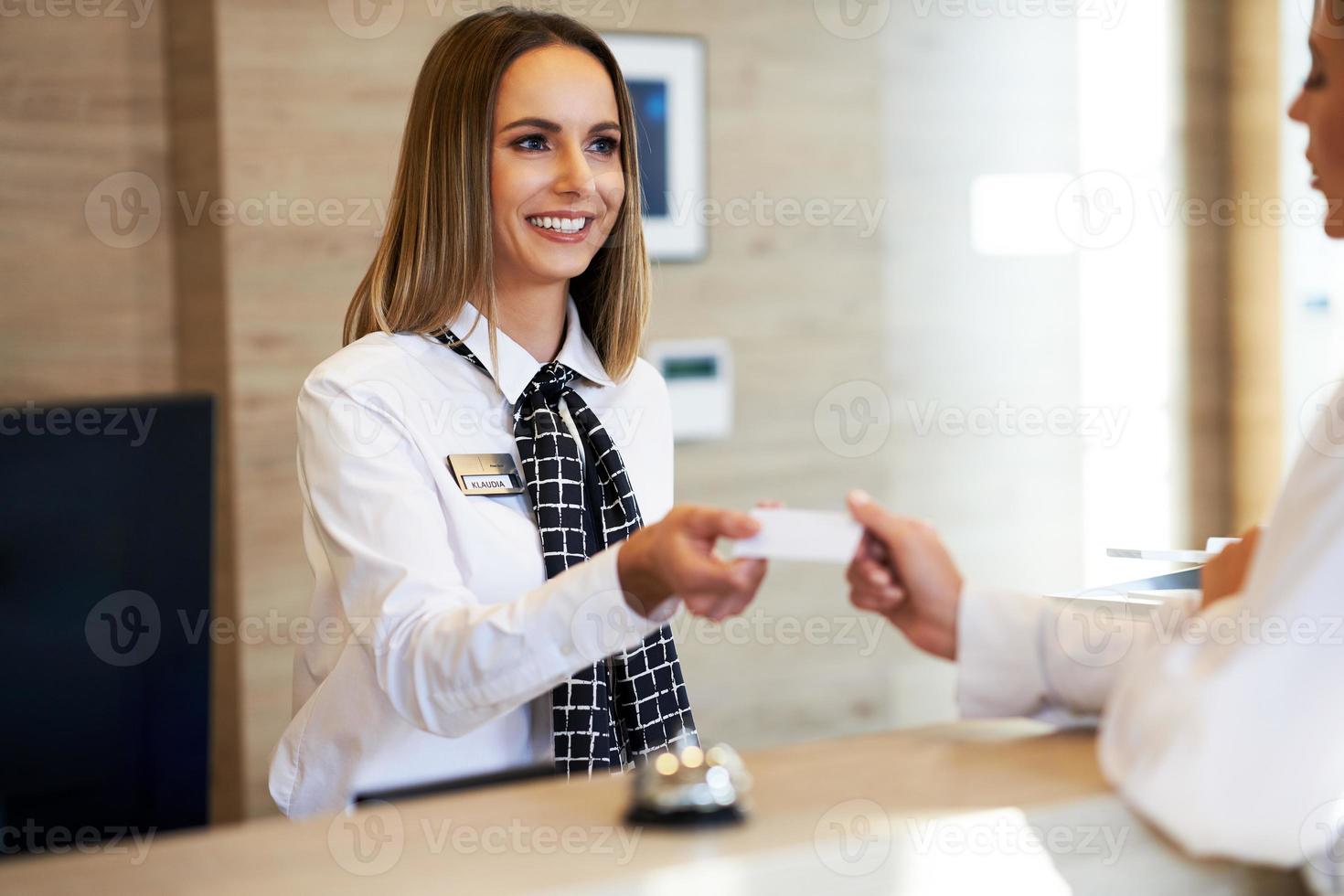 Receptionist giving key card to businesswoman at hotel front desk photo