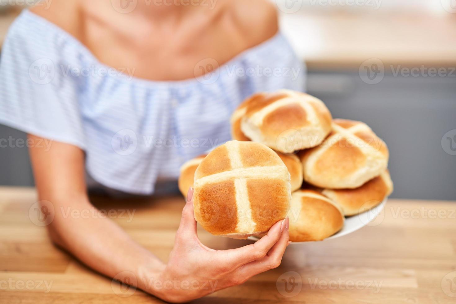 mujer adulta feliz preparando bollos cruzados calientes para pascua en la cocina foto