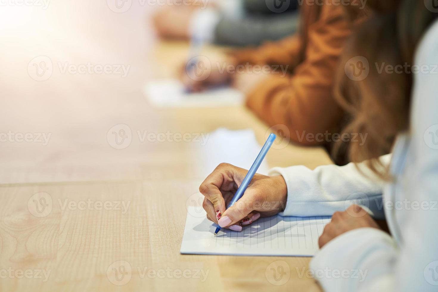 Picture of a human hand writing something on the paper on the foreground photo