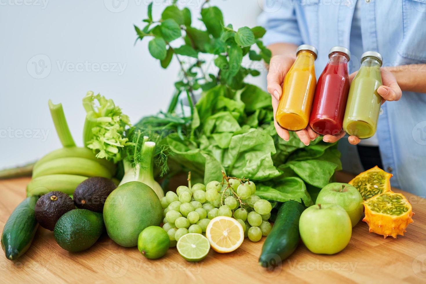 Bottle of smoothie oresh green fruit and vegetables on wooden counter photo