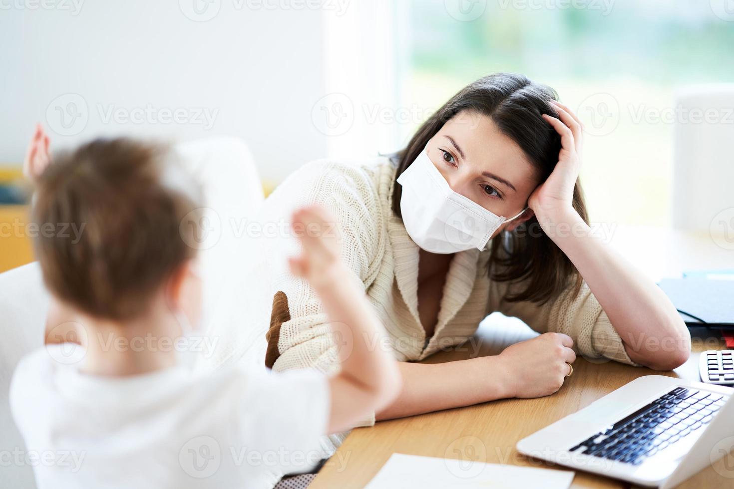 Boy and exhausted mother trying to work at home during coronavirus pandemic photo