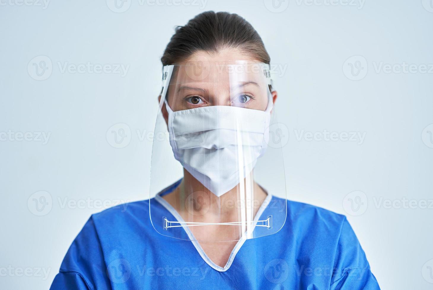 Portrait of female medical doctor wearing protective mask and face shield photo