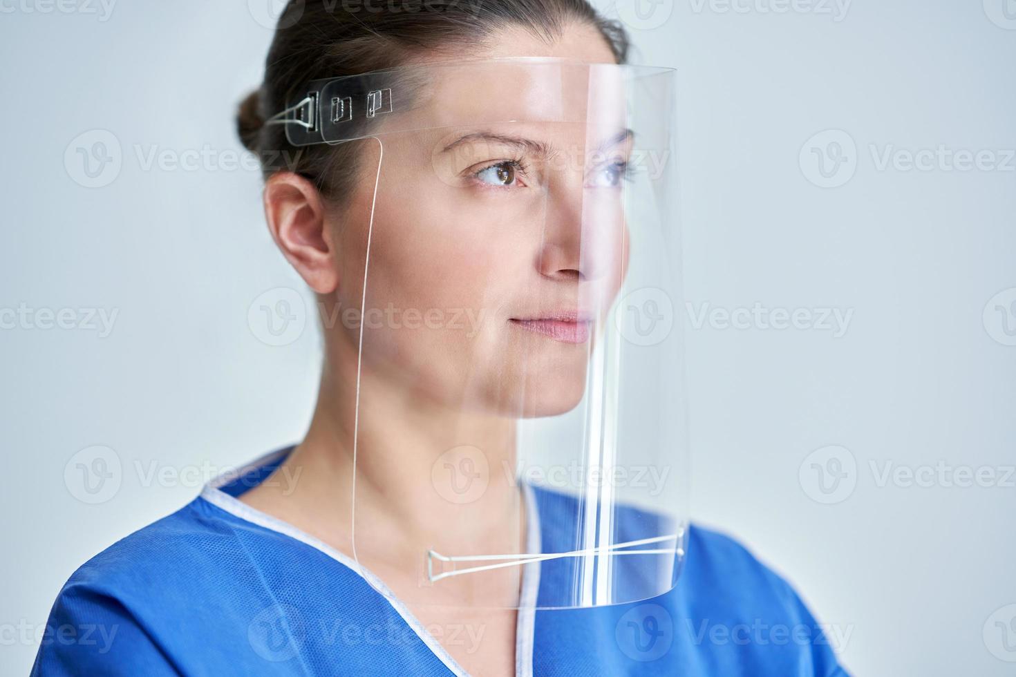 Close up portrait of female medical doctor or nurse wearing face shield photo