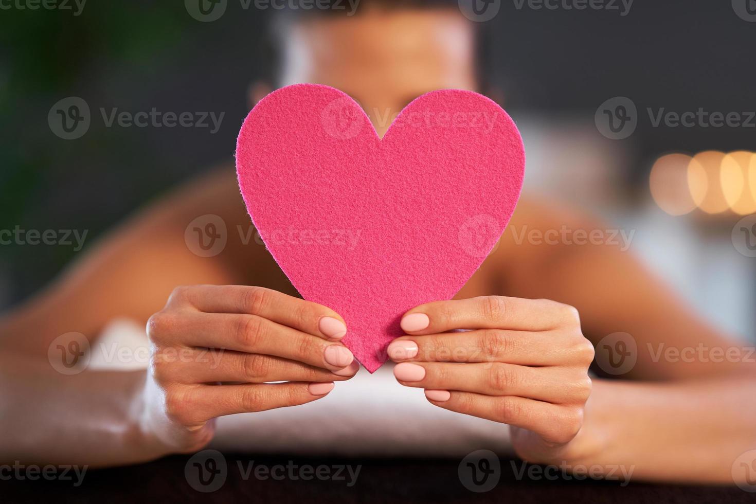 Relaxed woman waiting for a back massage and holding heart photo