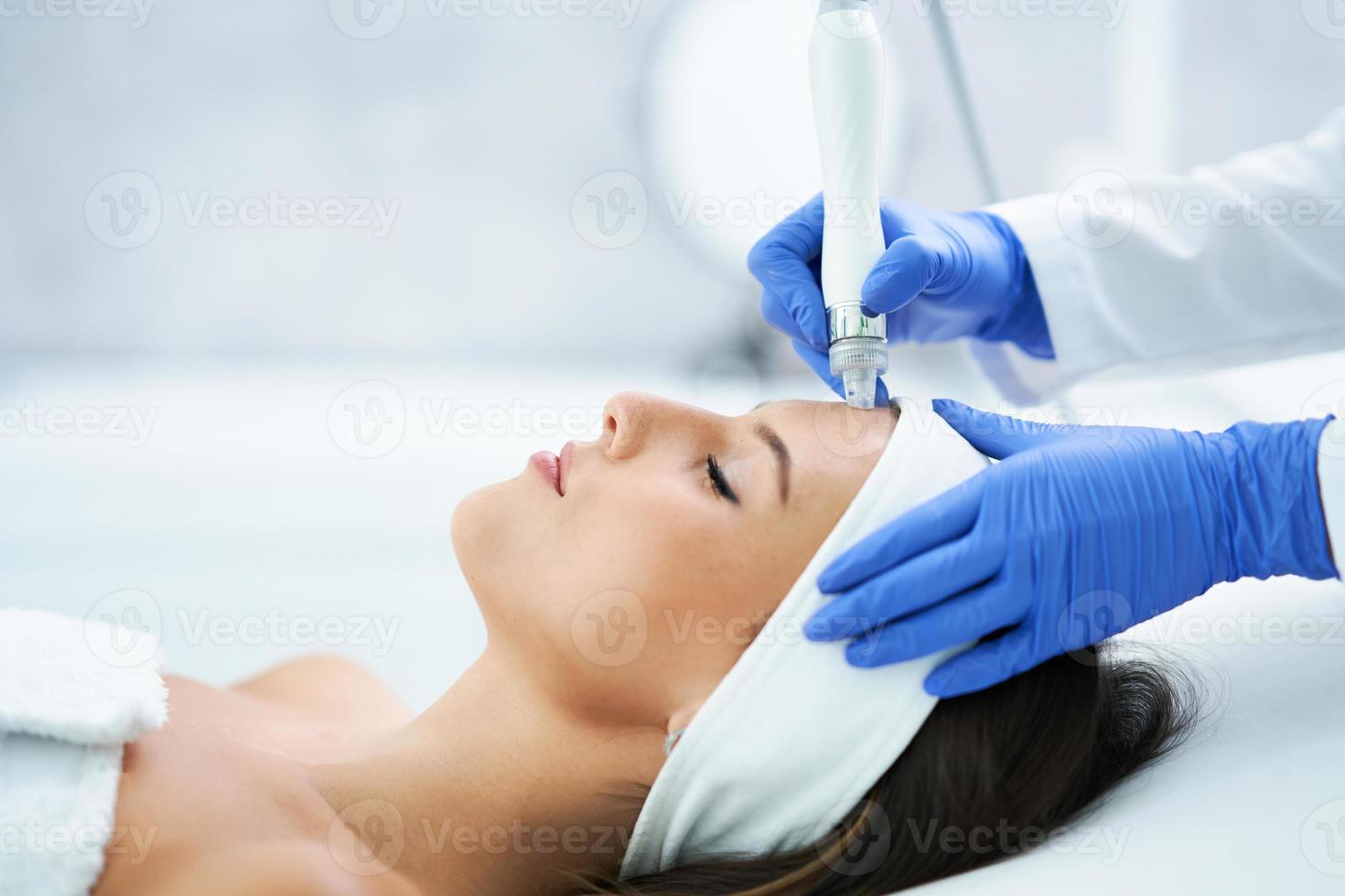 Beautiful young woman getting face treatment at beauty salon. photo