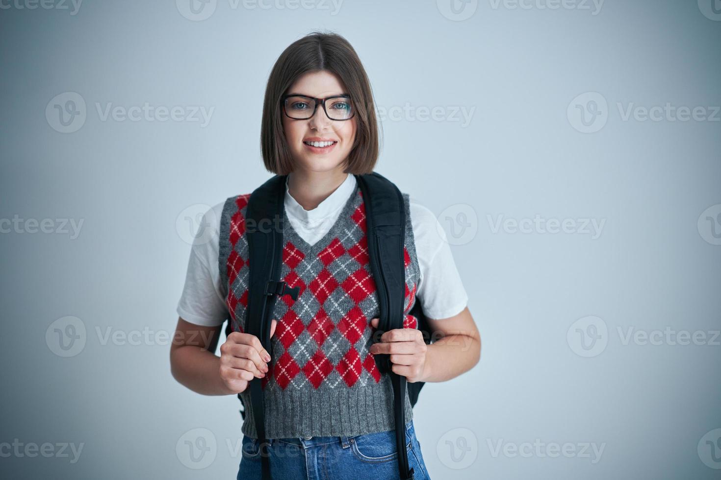 feliz joven estudiante positivo posando sobre un fondo brillante foto