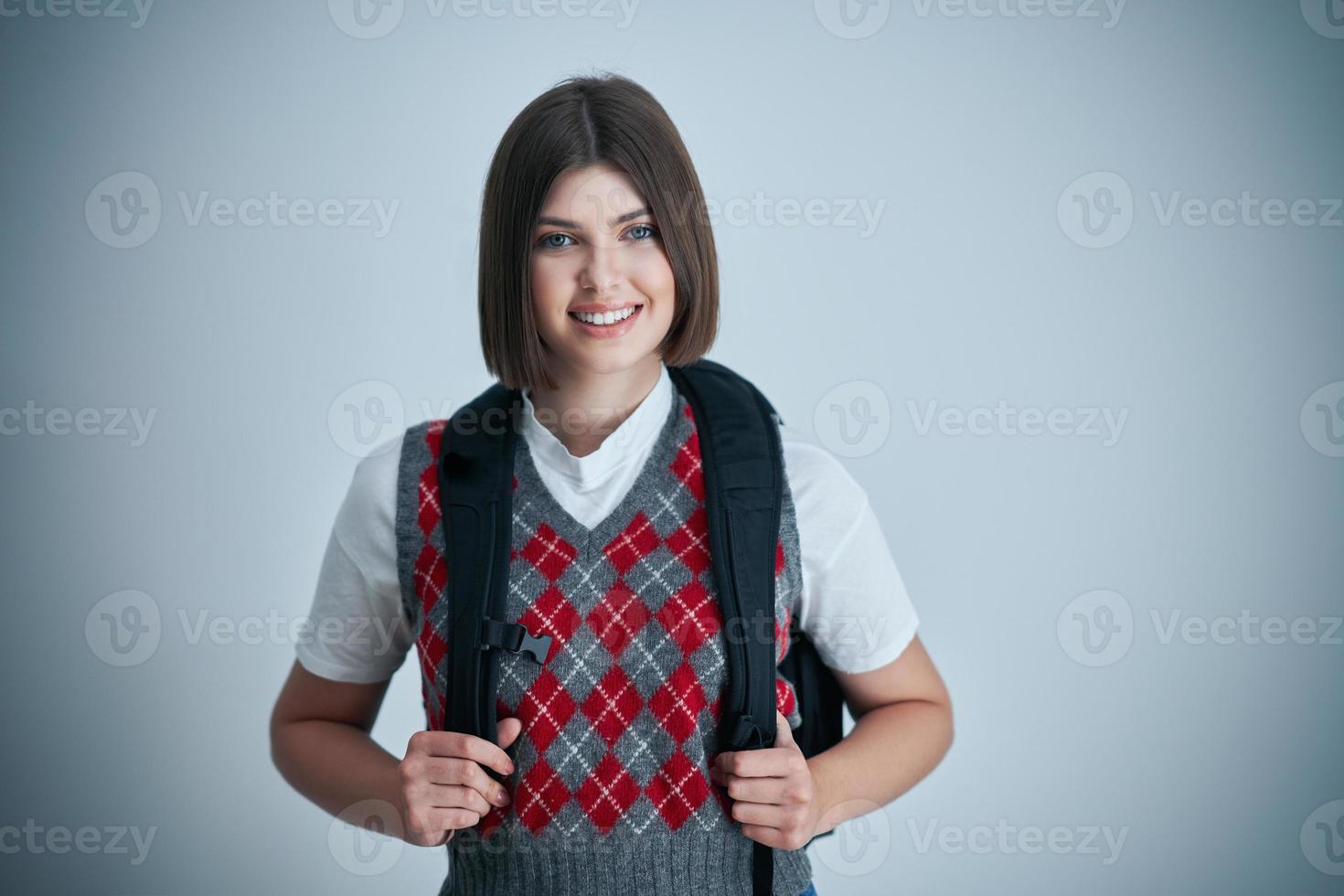 Happy young positive student posing over bright background photo