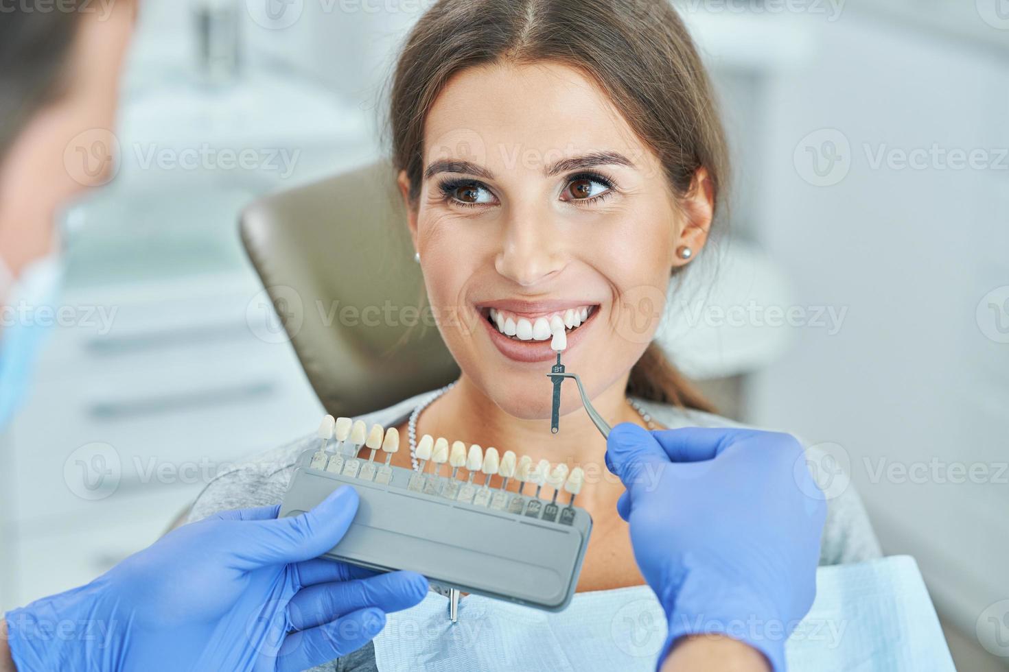 Male dentist and woman choosing tooth shade in dentist office photo