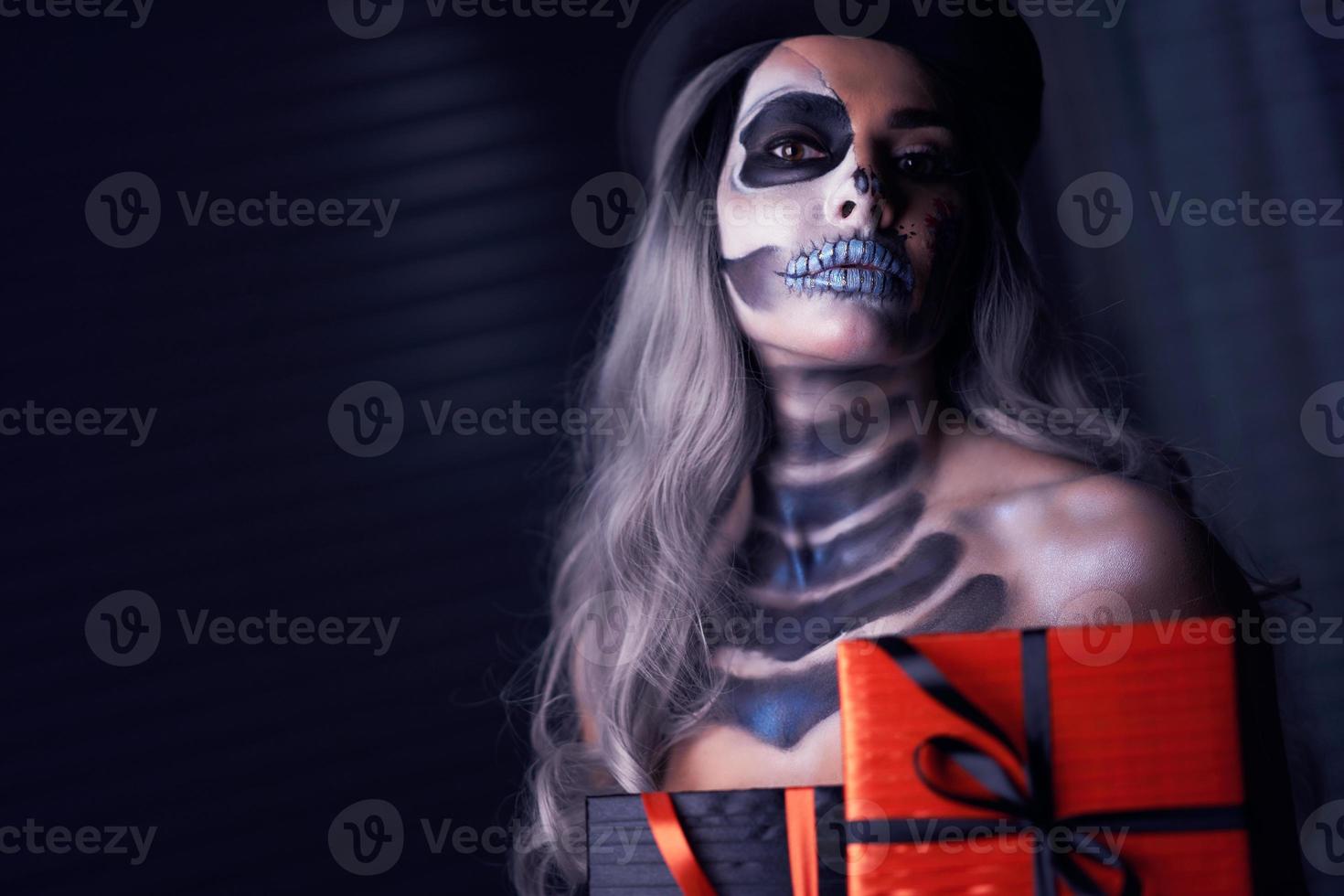 Spooky portrait of woman in halloween gotic makeup holding present photo