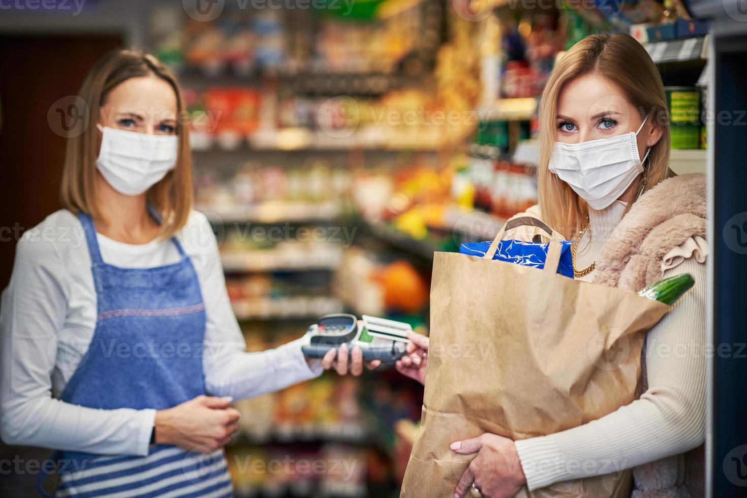 Adult woman in medical mask picking up order in grocery store photo