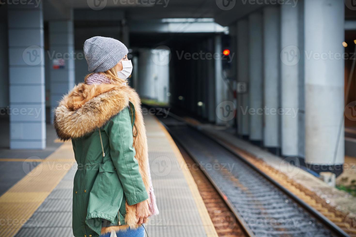 Adult woman at train station wearing masks due to covid-19 restrictions photo