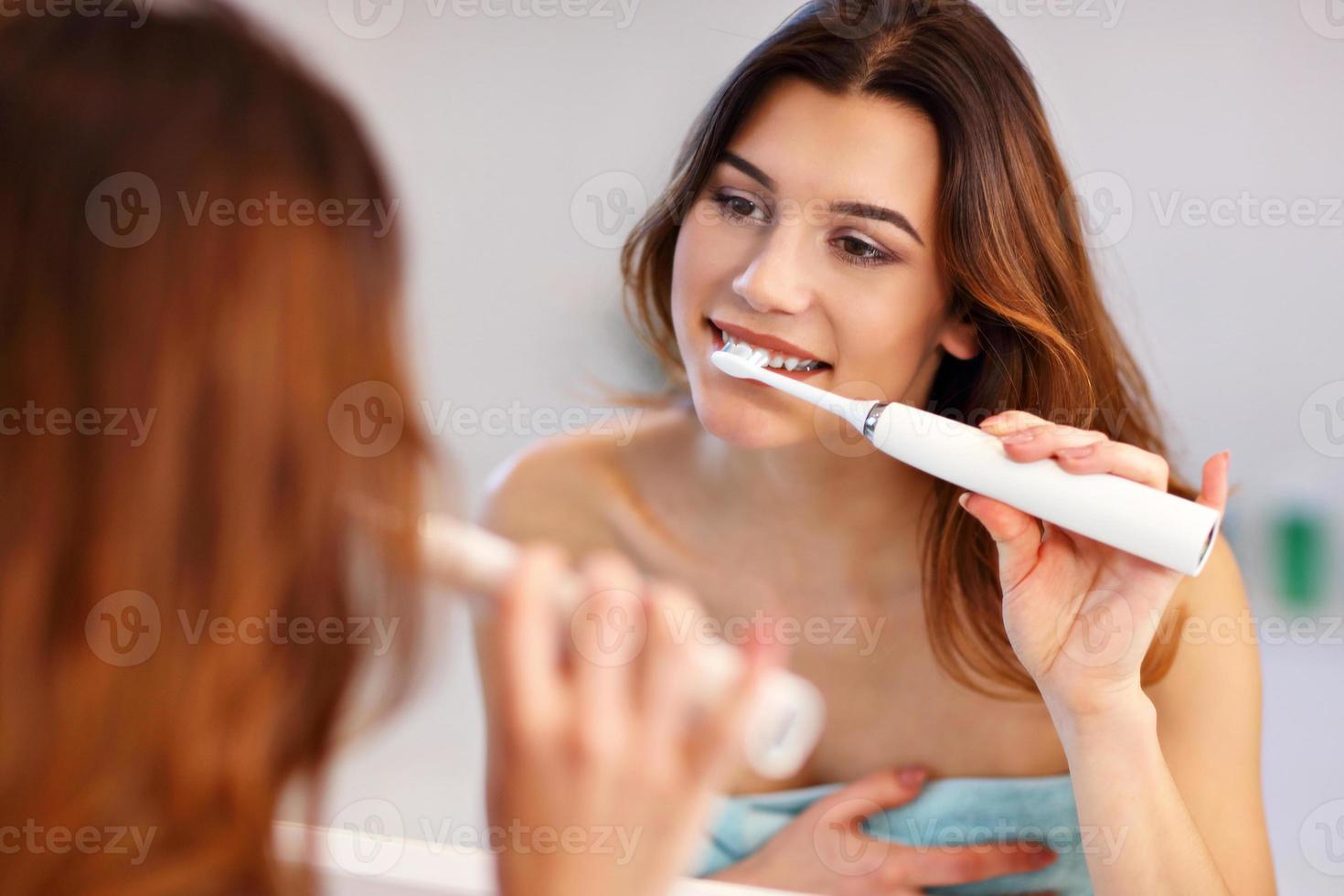 Young woman washing teeth in bathroom in the morning photo