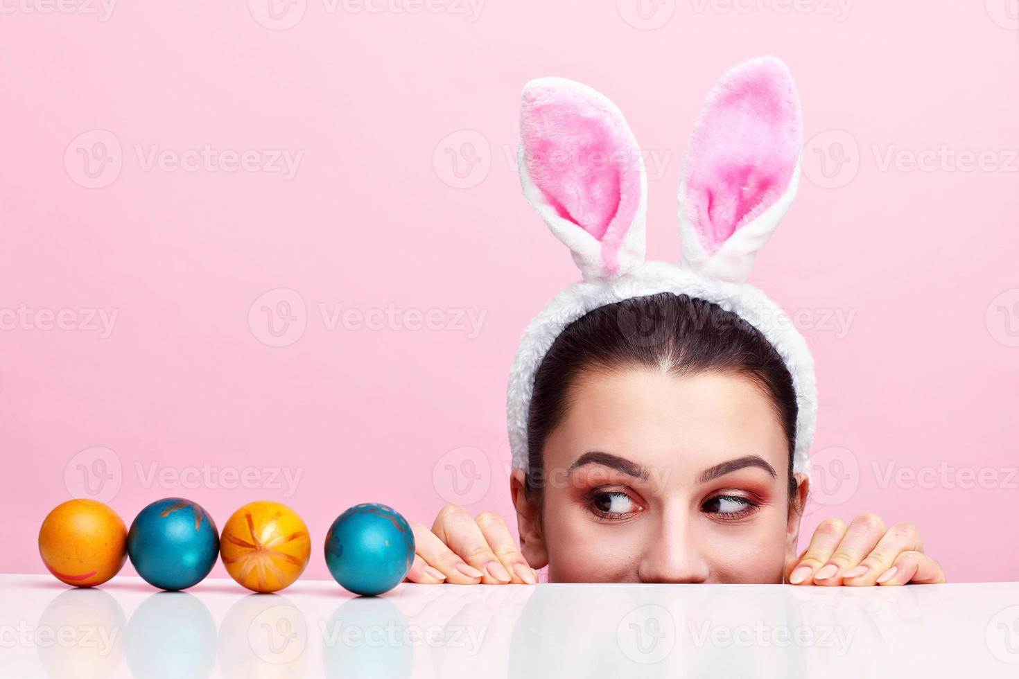 mujer joven feliz con orejas de conejo y huevos de Pascua foto