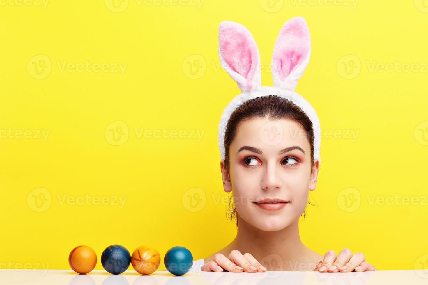 Happy young woman wearing bunny ears and having Easter Eggs photo