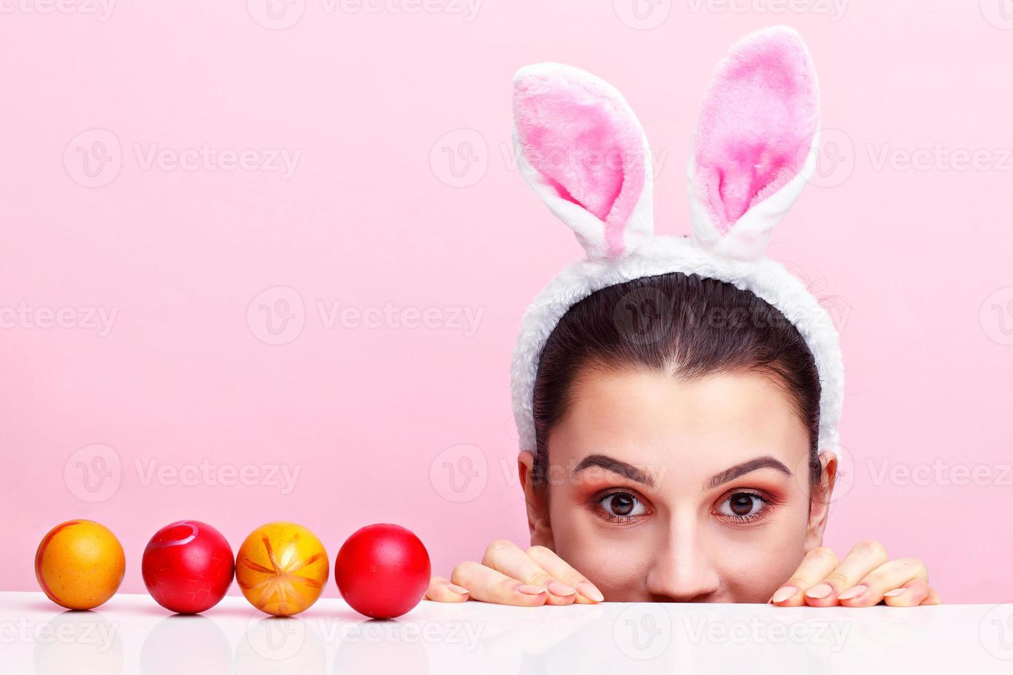 mujer joven feliz con orejas de conejo y huevos de Pascua foto