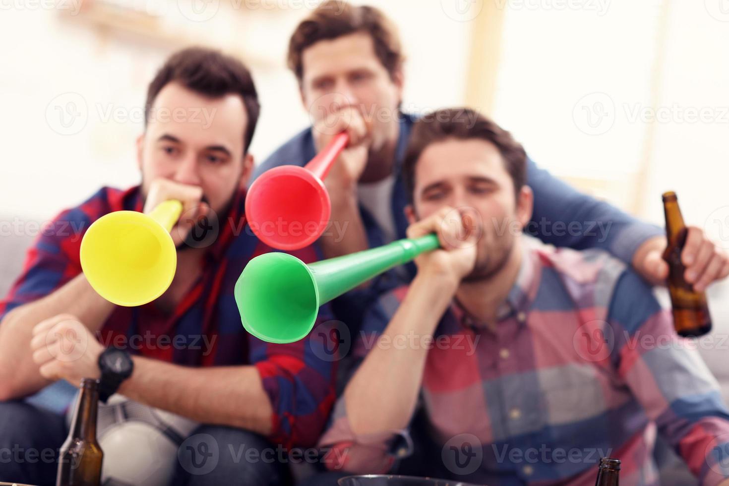 Happy male friends cheering and watching sports on tv photo