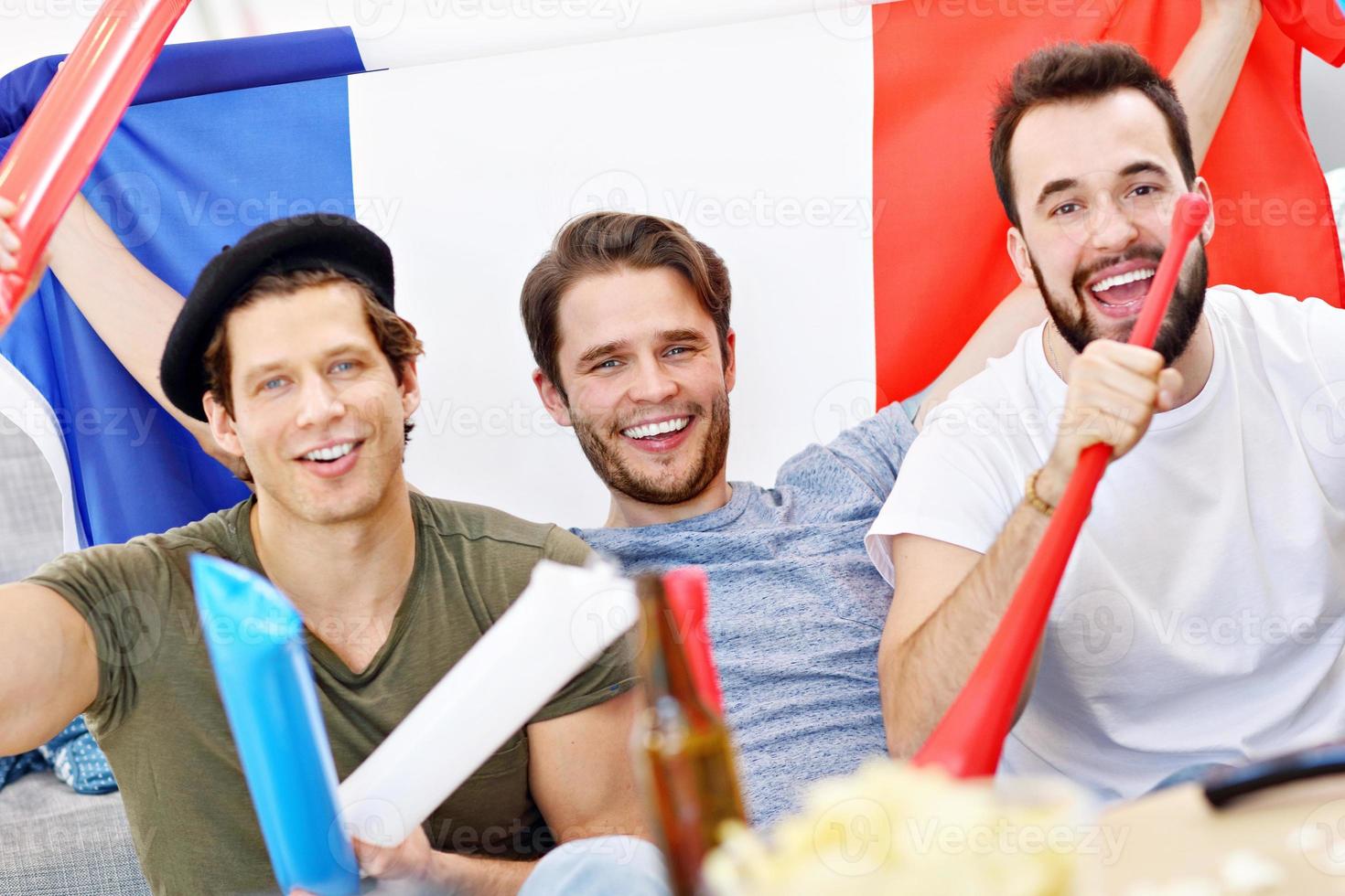 Happy male friends cheering and watching sports on tv photo