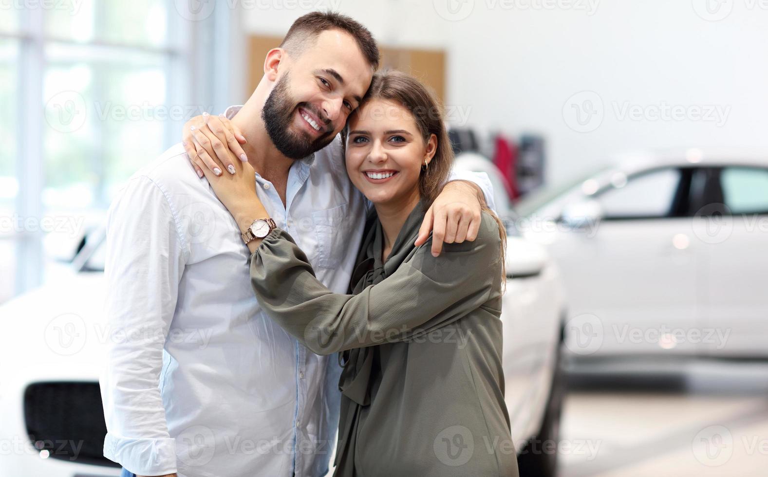 Adult couple choosing new car in showroom photo