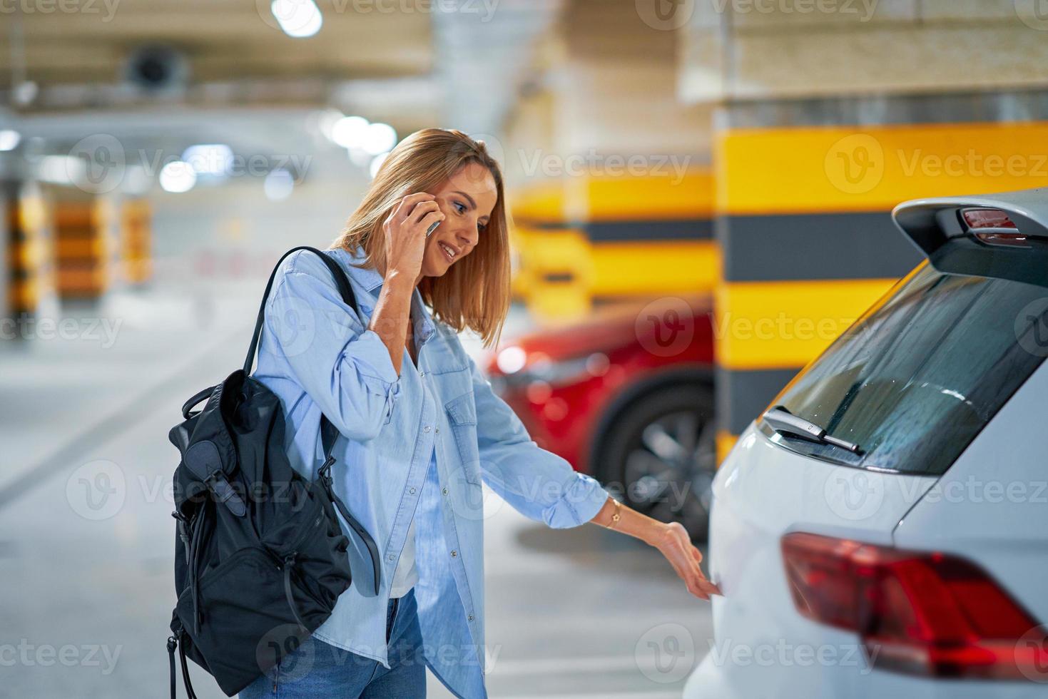 Adult woman using cellphone in underground parking lot photo