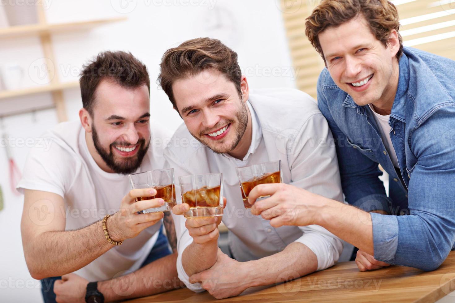 Cheerful friends having fun with smartphone and drinking at home photo