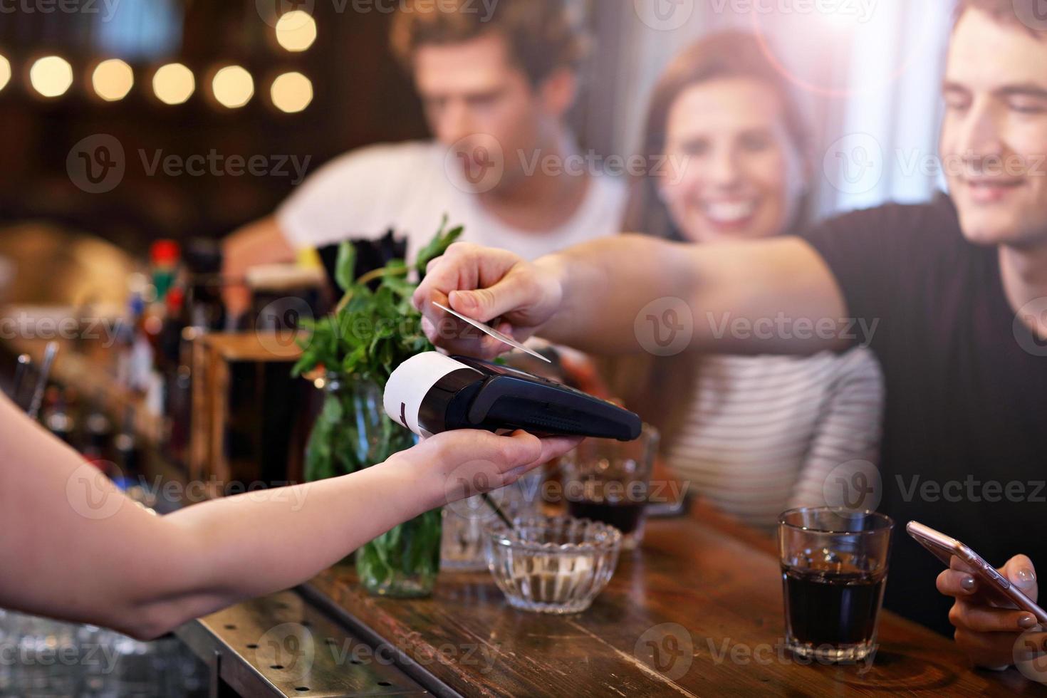 Group Of Friends Paying For Meal In Restaurant photo