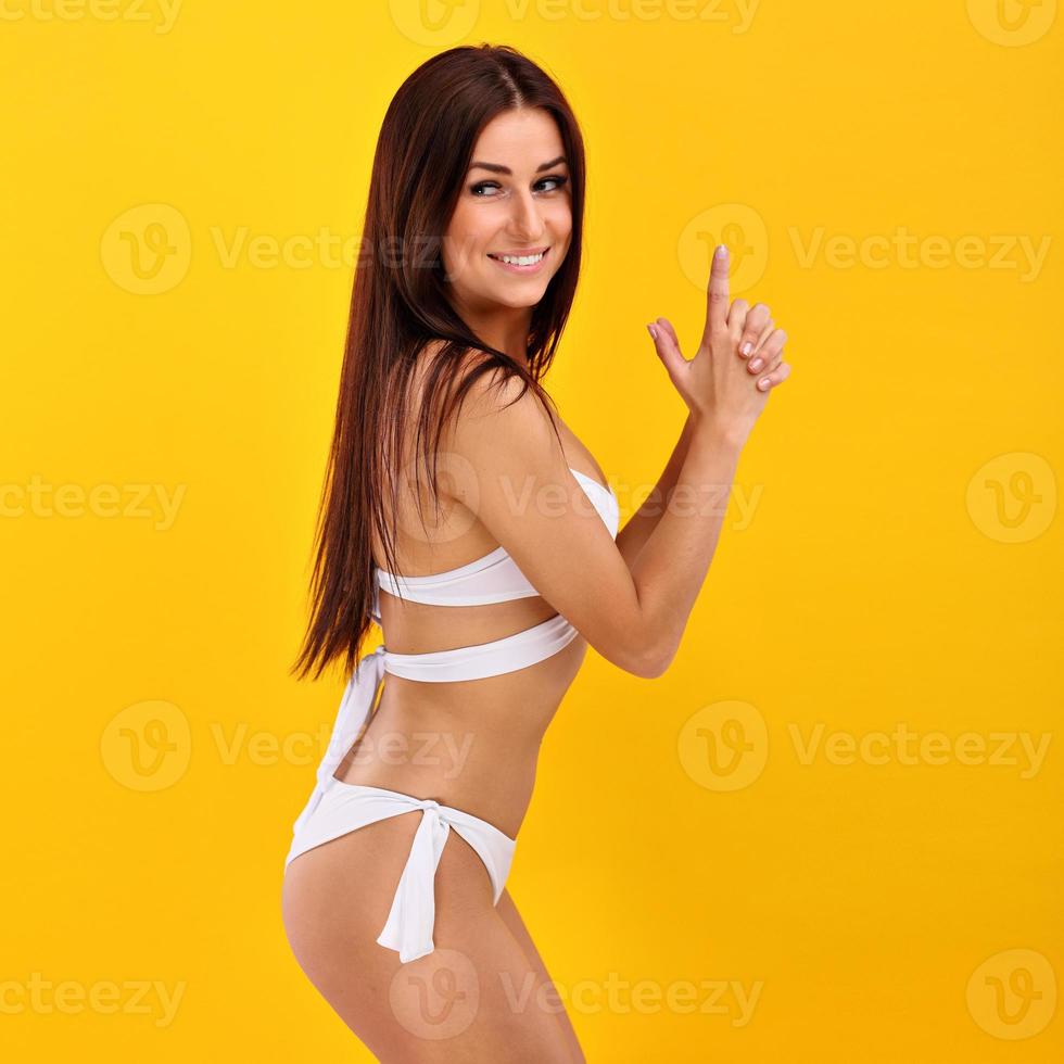 Sexy woman in bikini posing against yellow background photo