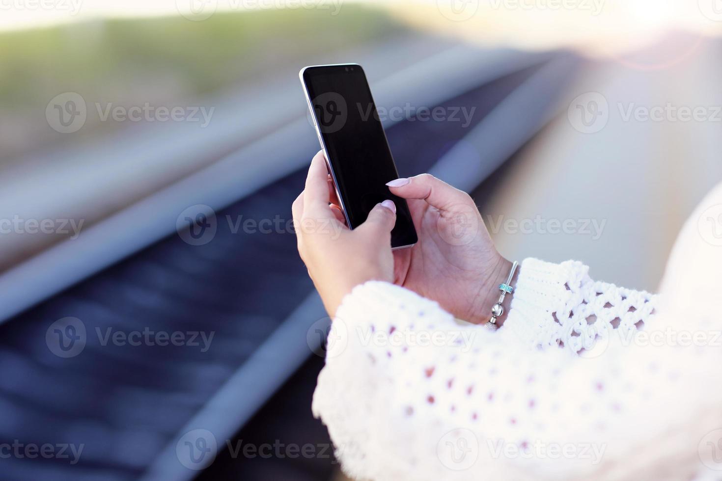 Hand holding smartphone with railway station background photo