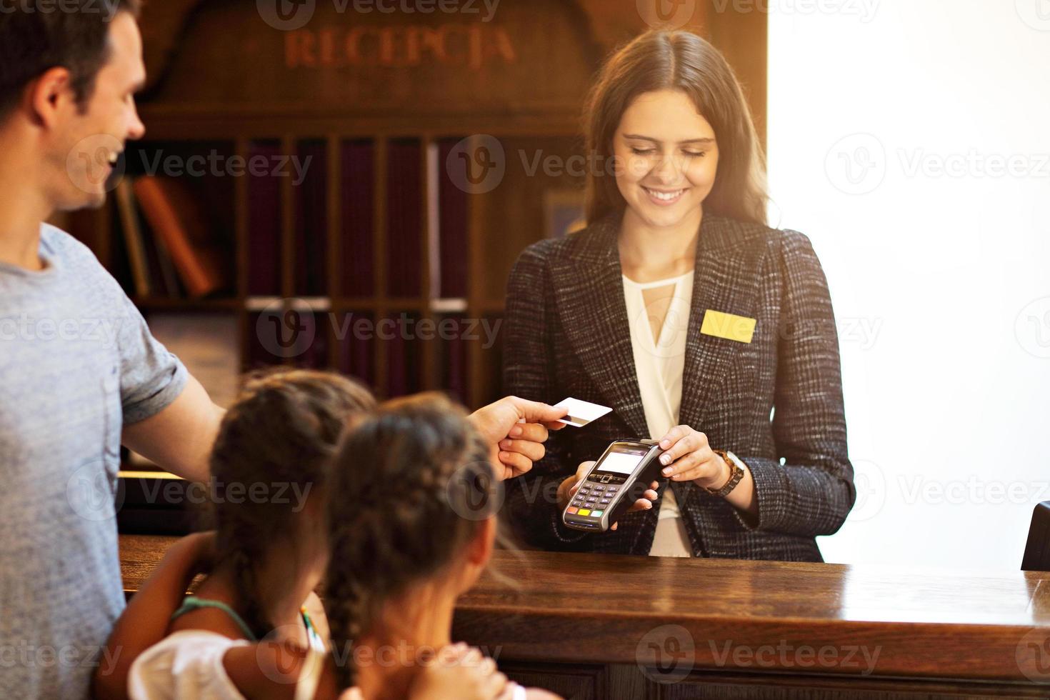 Happy family checking in hotel at reception desk photo