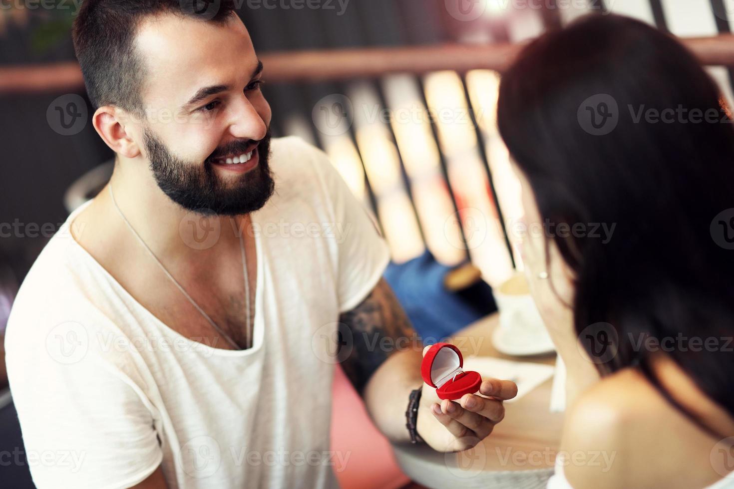 Handsome man proposing to beautiful woman in cafe photo