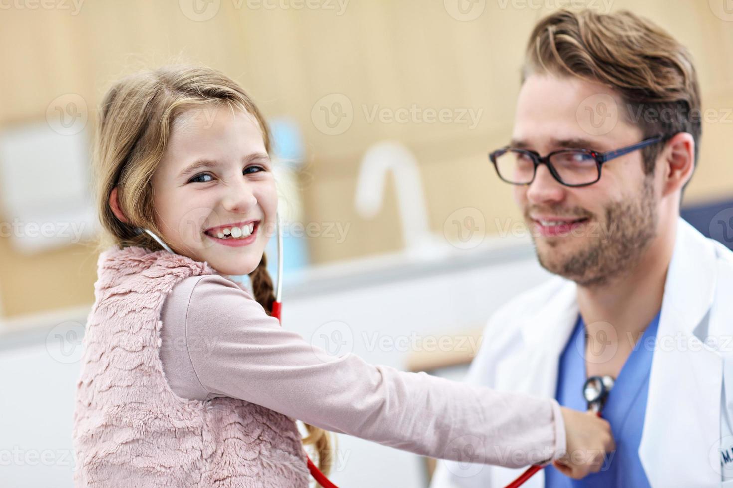 Little girl in clinic having a checkup with pediatrician photo