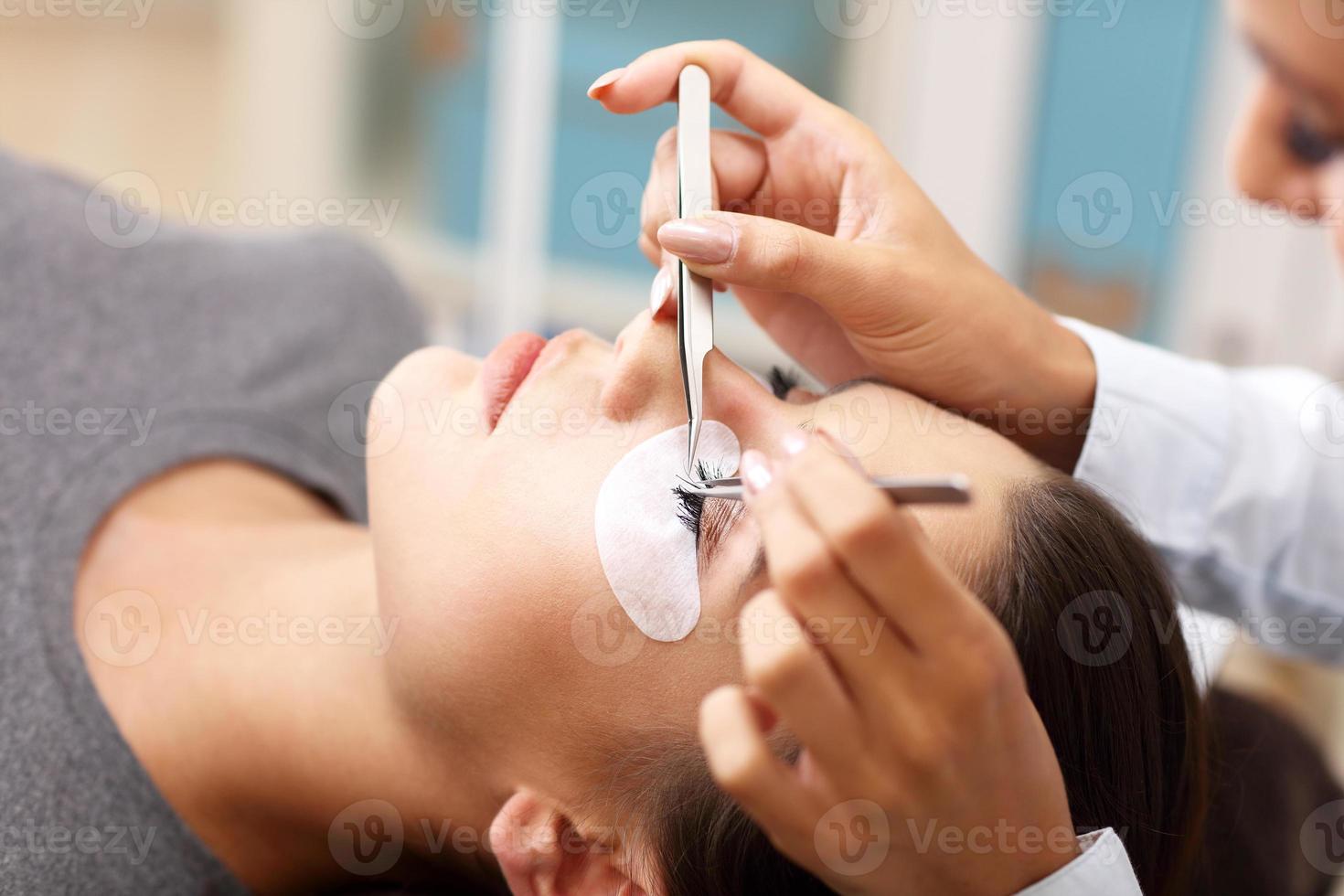 Adult woman having eyelash extension in professional beauty salon photo