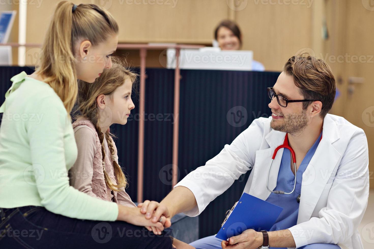 Doctor welcoming mother and daughter in clinic photo