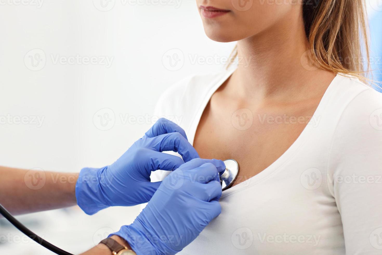 Adult woman being examined with stethoscope by female doctor photo