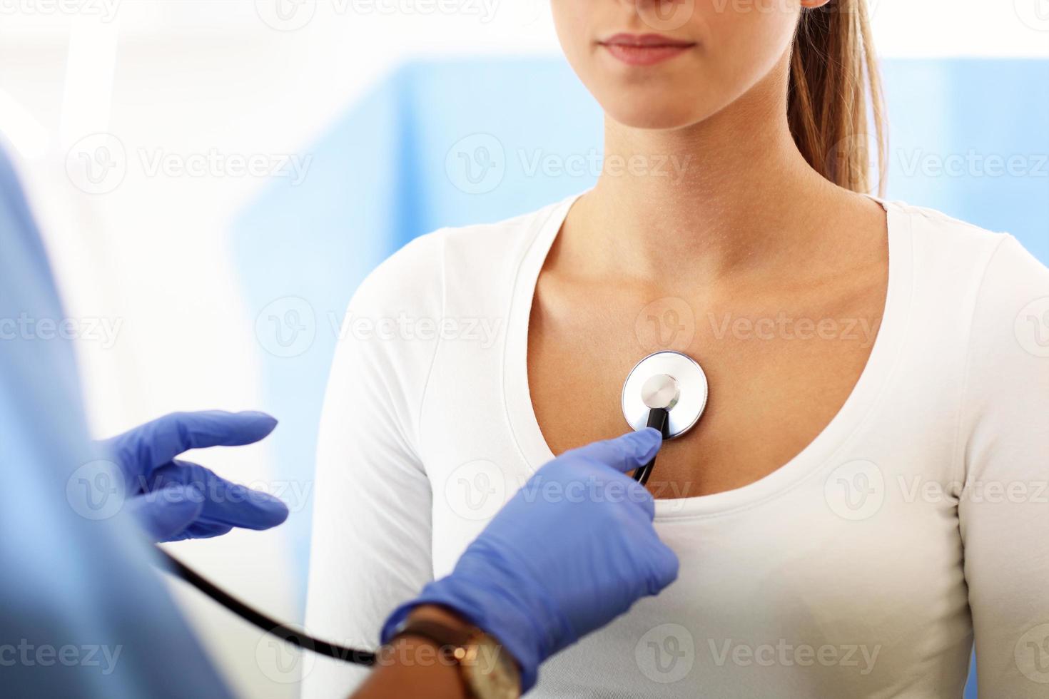 Adult woman being examined with stethoscope by female doctor photo