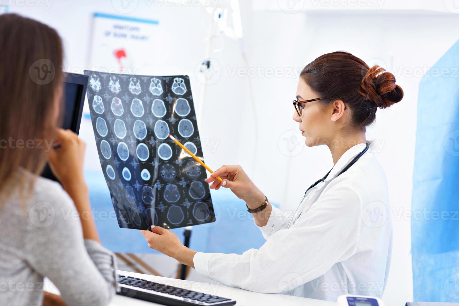 mujer adulta discutiendo los resultados de rayos X durante la visita al consultorio de una doctora foto